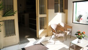 Una habitación con sillas de mimbre, una mesita pequeña y una planta en maceta.