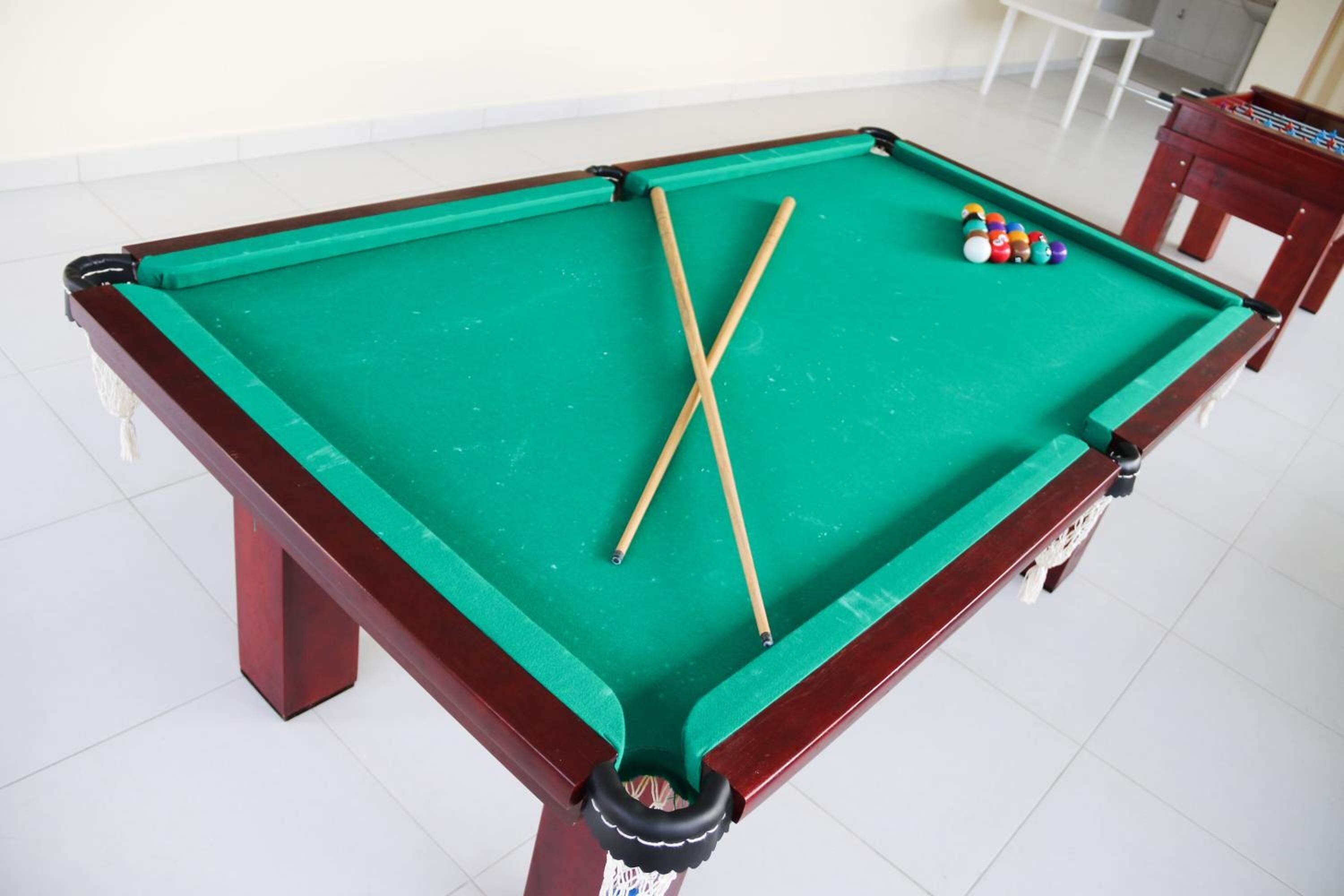 Una mesa de billar con dos tacos y un juego de bolas de billar.
