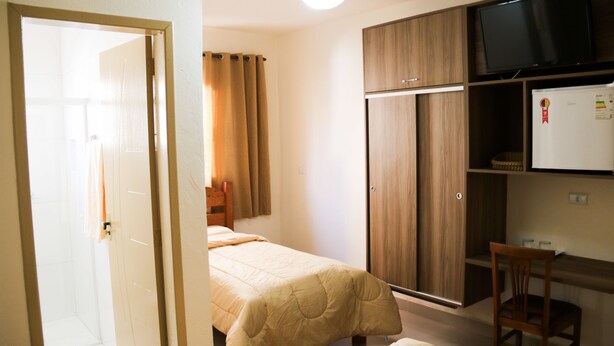 Un dormitorio con dos camas, un armario de madera, un televisor y un refrigerador.