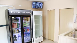 A minibar area with a refrigerator labeled "Fríos e Latínicos" containing various beverages. - Hotel Vale das Artes (Embu das Artes)