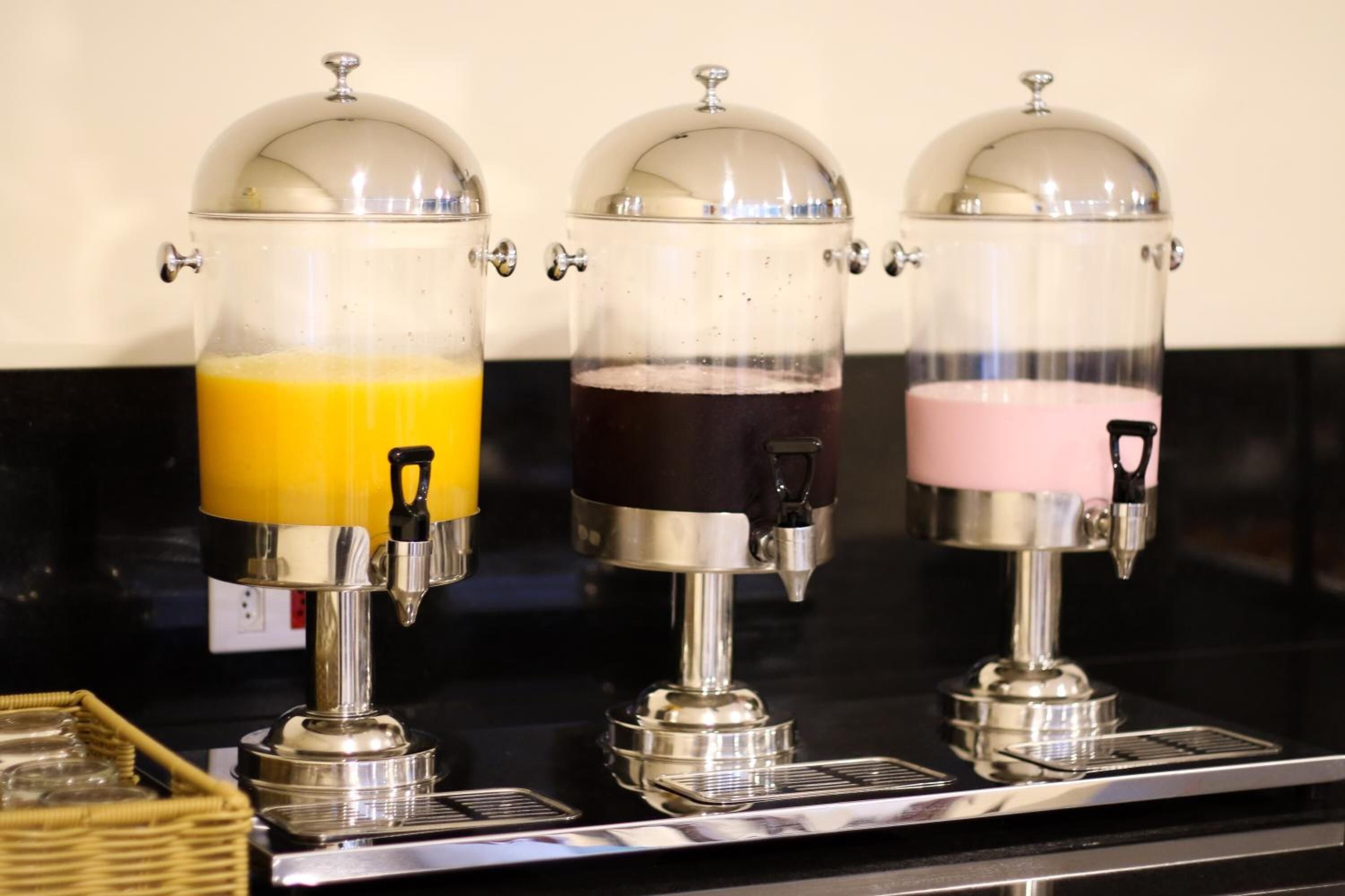 A coffee machine with three dispensers, each with a different colored liquid.