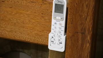 A white Midea air conditioner unit with a digital display, control buttons, and a remote control.