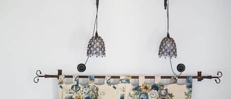 A bedroom with a wooden ceiling, a bed with floral bedding, and two wall-mounted lamps.