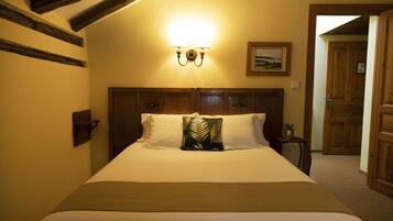 Ein Hotelzimmer mit einem großen Bett, einem Holzkopfende und einer wandmontierten Leuchte.