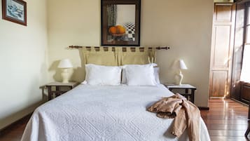 Una cama bien hecha con una colcha blanca y dos mesitas de noche con lámparas.