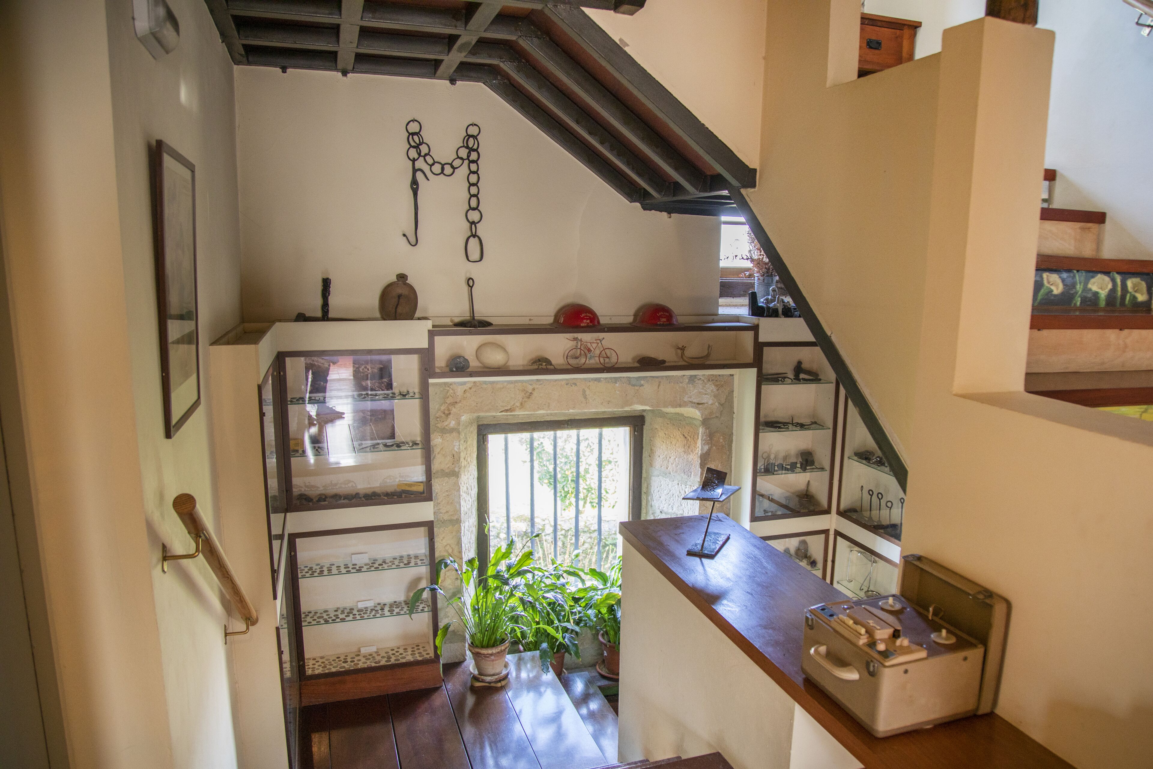 A cozy room with a wooden staircase, a fireplace, and a variety of decorative items on shelves.