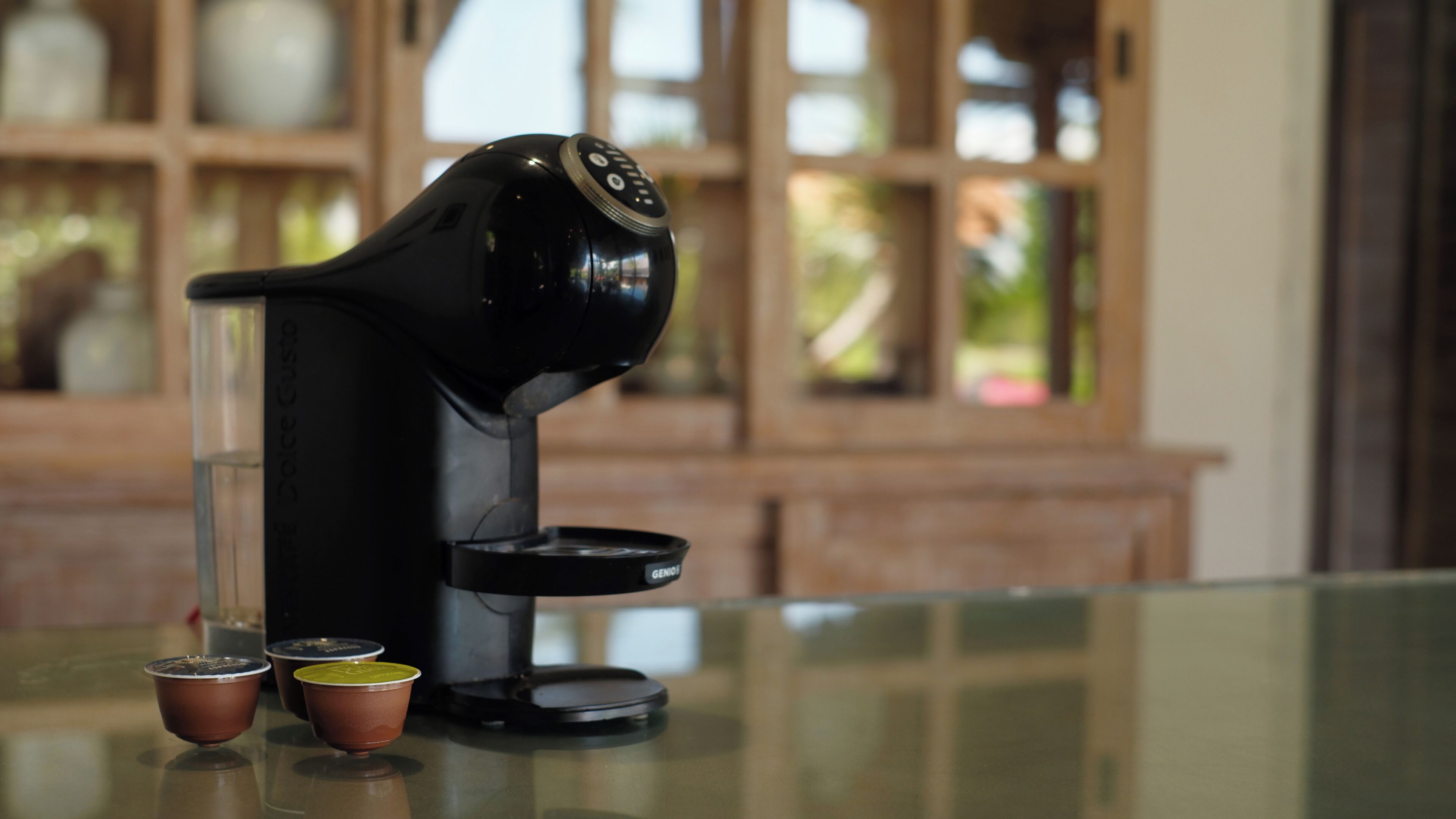 Máquina de café sobre mesa de vidro, com duas chávenas ao lado.