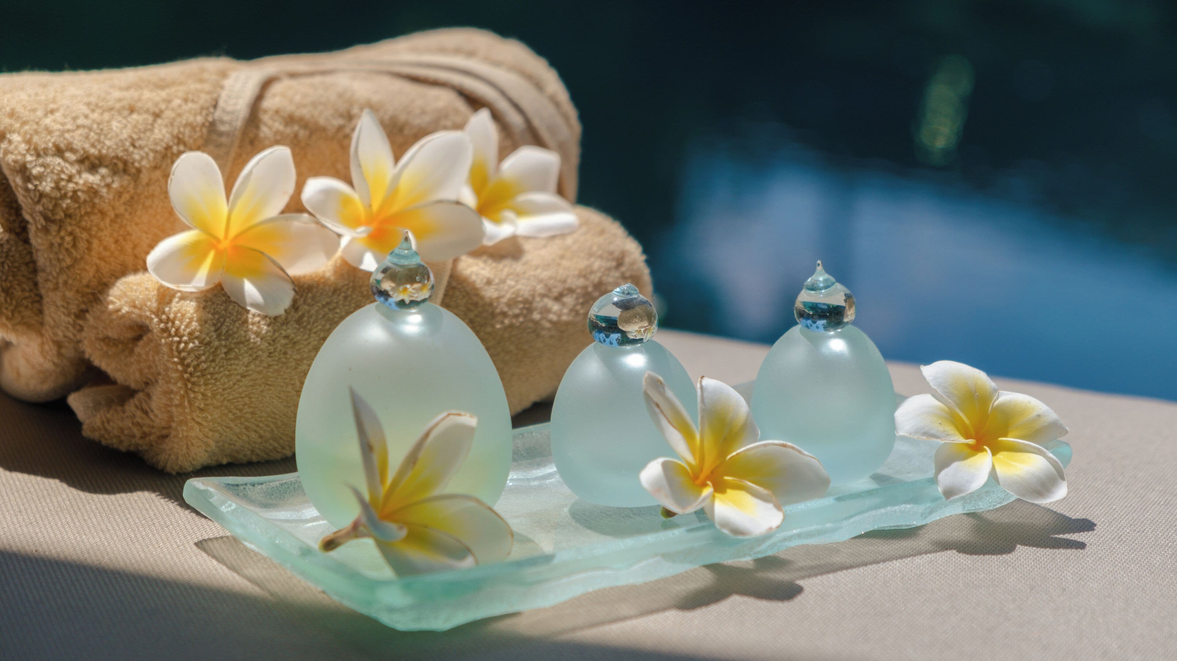 Un ambiente de spa con una toalla, botellas de vidrio y flores.