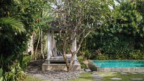 A garden with a gazebo, a swimming pool, and lush greenery. - Villa Little Mannao by Villa Finder (Kerobokan)