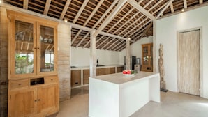 A modern kitchen with wooden cabinets, a central island, and a rustic ceiling. - Villa Du Ho by Villa Finder (Kerobokan)