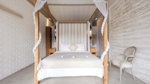 A bedroom with a four-poster bed, a wooden chair, and a brick wall. - Villa Du Ho by Villa Finder (Kerobokan)