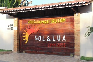 A wooden door with the text "POUSADAPARACURU.COM" and "SOL&LUA 3344 2055".