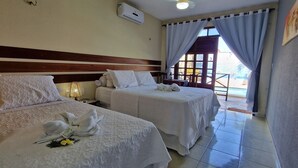 A hotel room with two beds, each with a white bedspread and pillows, a bedside table with a lamp, and a window with curtains. - Hotel Pousada Sol & Lua (Paracuru)