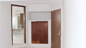 Habitació amb armari de fusta, una porta i un mirall que reflecteix un bany amb un lavabo i un mirall.