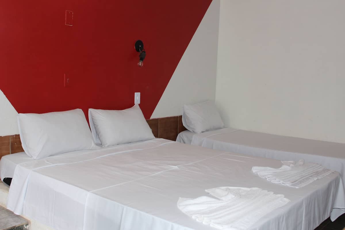 A hotel room with two beds, white bedding, and a red accent wall.