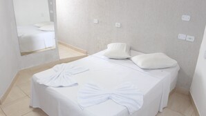 Una habitació d'hotel amb un llit ben fet, un mirall i una paret amb interruptor i presa.
