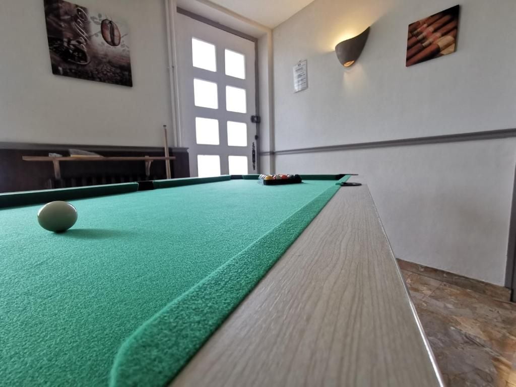 Una mesa de billar con superficie de fieltro verde, una bola blanca y un juego de tacos.