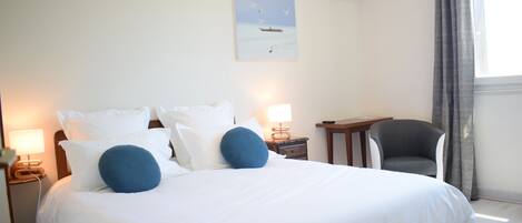 A hotel room with a large bed, a desk, a chair, and a painting on the wall.