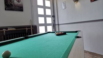 Una mesa de billar con bolas, una puerta y decoración en la pared.