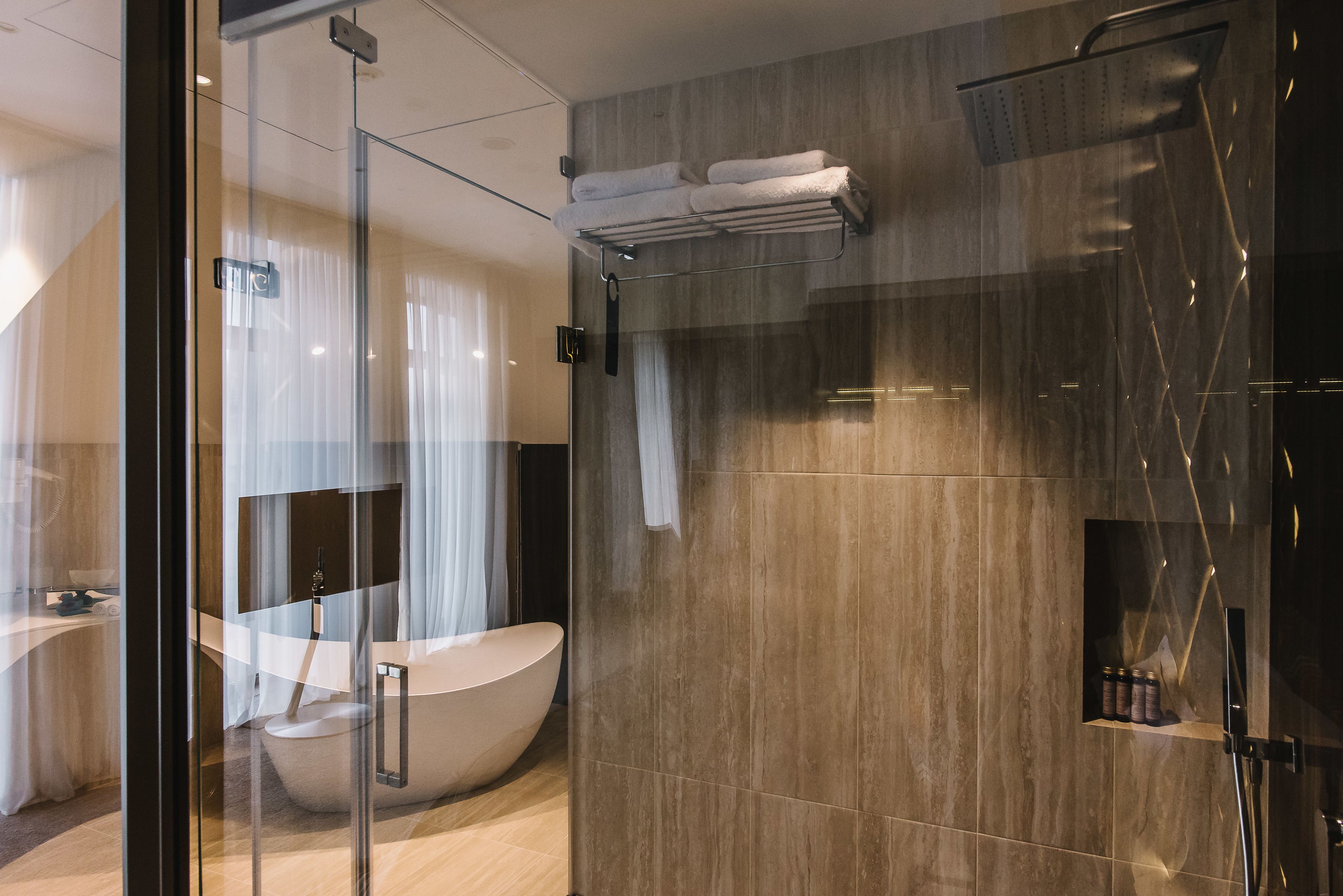 A modern bathroom with a freestanding bathtub, a glass shower enclosure, and a towel rack with folded towels.