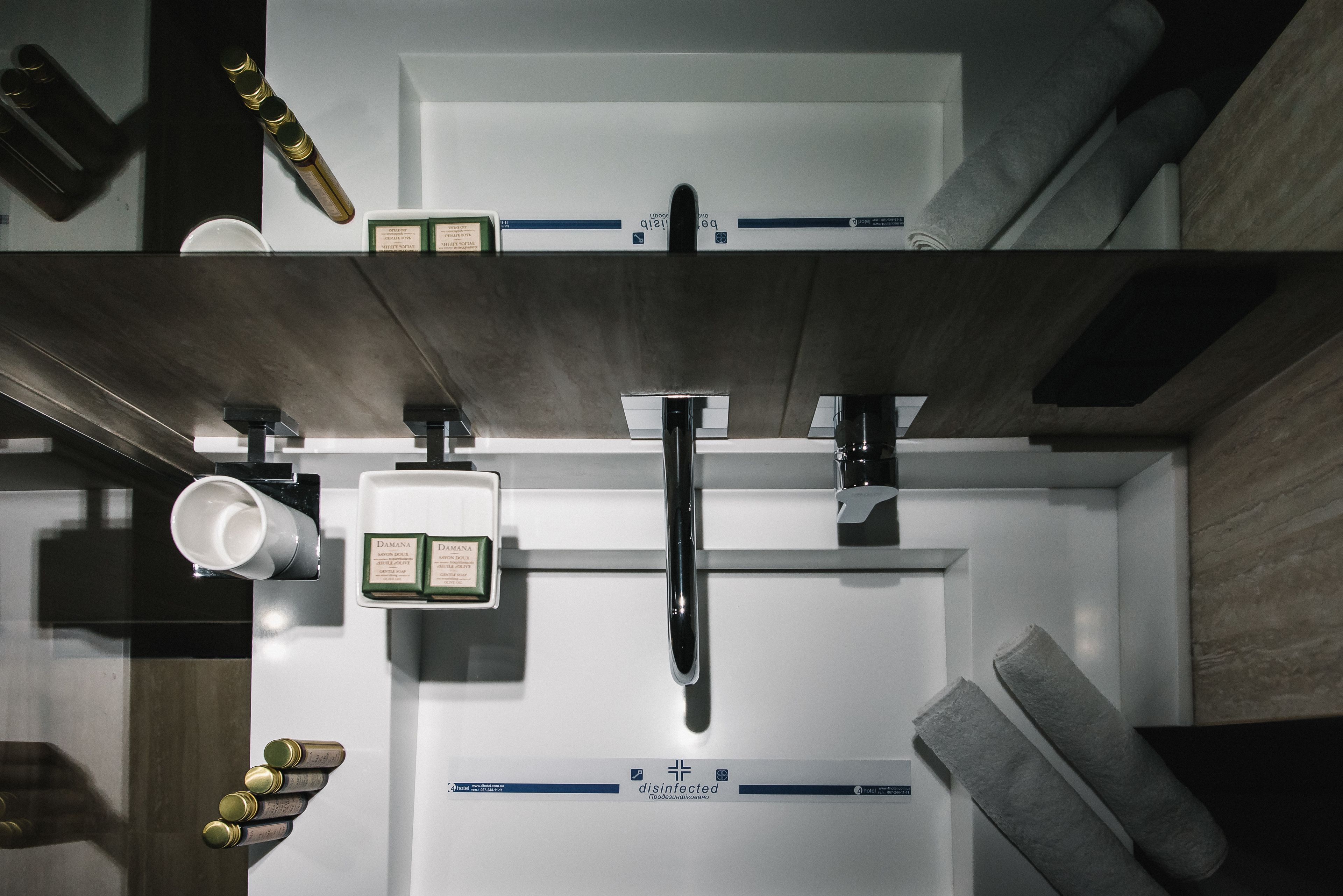 Ein modernes Badezimmer mit einem Edelstahlwaschbecken, einer Toilette und einem Bidet. An der Wand befinden sich Handtücher und ein Seifenspender.