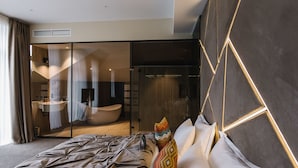 A modern bedroom with a large bed, a glass shower enclosure, and a visible bathroom with a bathtub. - Noble Boutique Hotel (Lutsk)