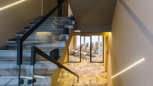 A modern staircase with glass railings and a marble floor leading to a room with a large window and a seating area. - Noble Boutique Hotel (Lutsk)