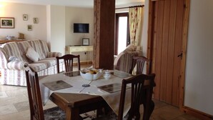 A dining area with a round table, chairs, and a television in the background. - Marsh Farm (Rugeley)