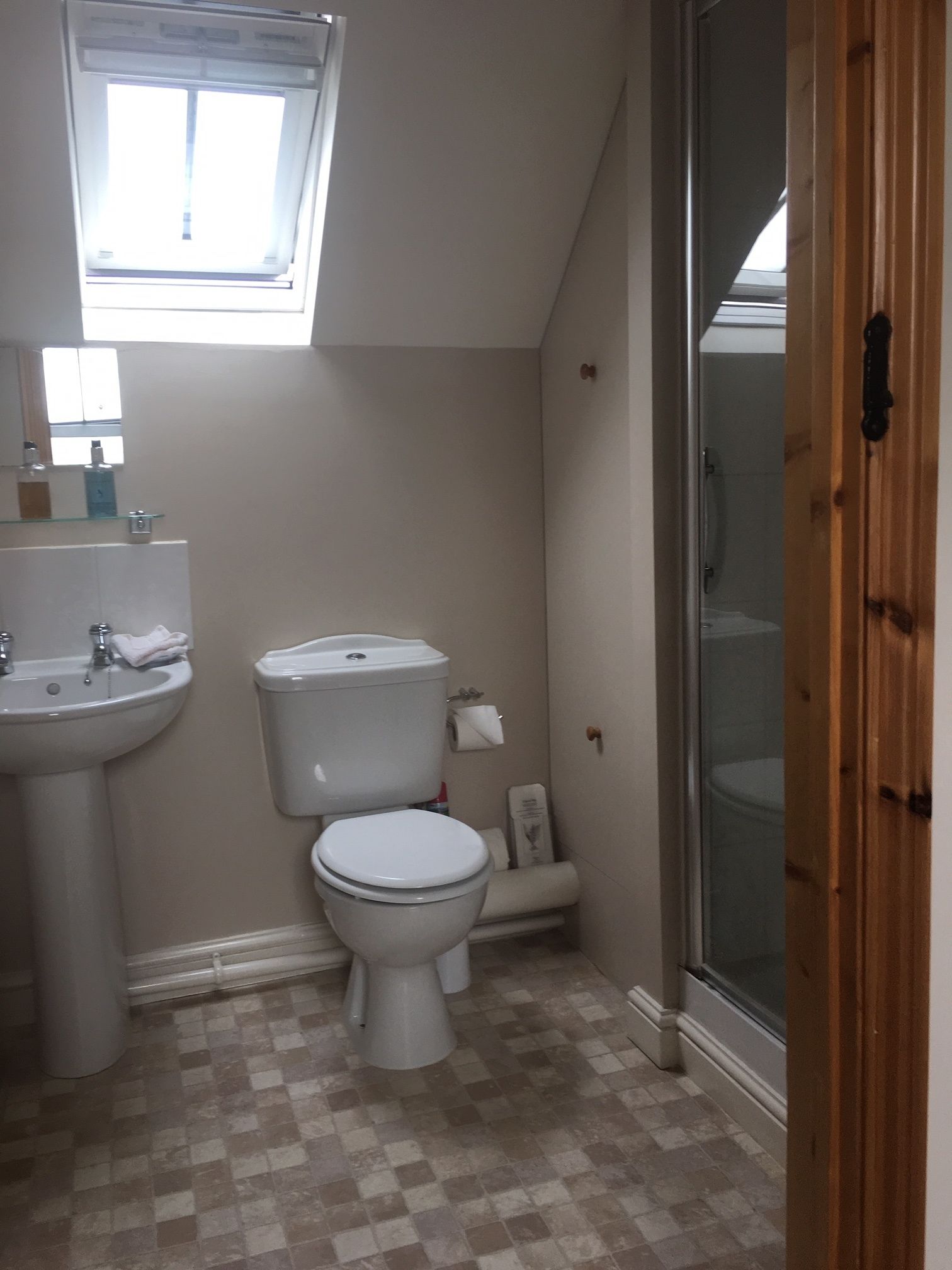 Un baño pequeño con inodoro, lavabo y ventana sobre el lavabo.