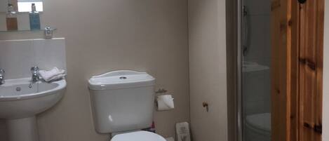 A small bathroom with a toilet, sink, and a window above the sink.