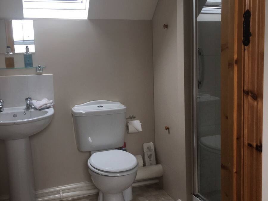 A small bathroom with a toilet, sink, and a window above the sink.
