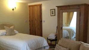 A bedroom with a bed, a wooden wardrobe, a chair, and a mirror reflecting a bed. - Marsh Farm (Rugeley)