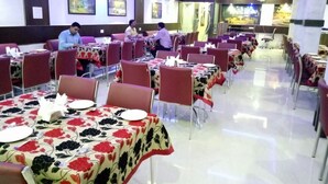 A restaurant with tables set for dining, chairs, and a clean, modern interior. - Hotel Embassy International (Muzaffarpur)
