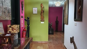A hallway with a green wall, a wooden statue, and a ceiling with a decorative light fixture. - Villa Mango (Abidjan)