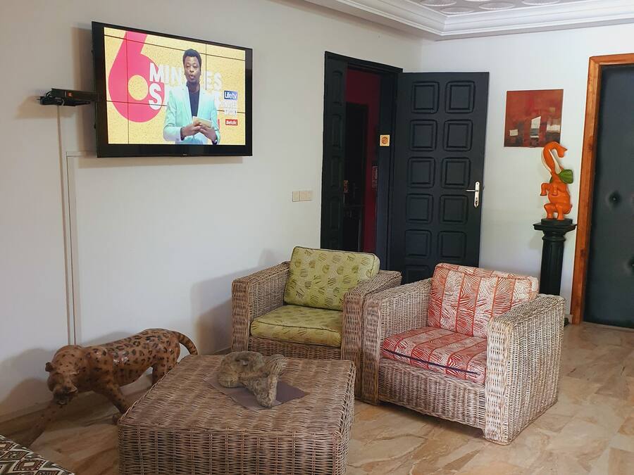 A living room with wicker furniture, a television mounted on the wall, and a door with a decorative handle.