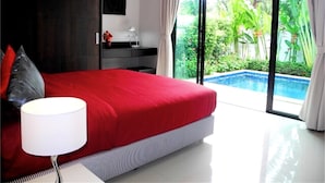 A modern bedroom with a large bed, a nightstand, a desk, and a view of a swimming pool. - Intira Villa Rawai 2 bedrooms villa (Rawai)