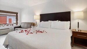 Una camera d'albergo con un letto grande, due lampade ai comodini, una sedia e una scrivania.