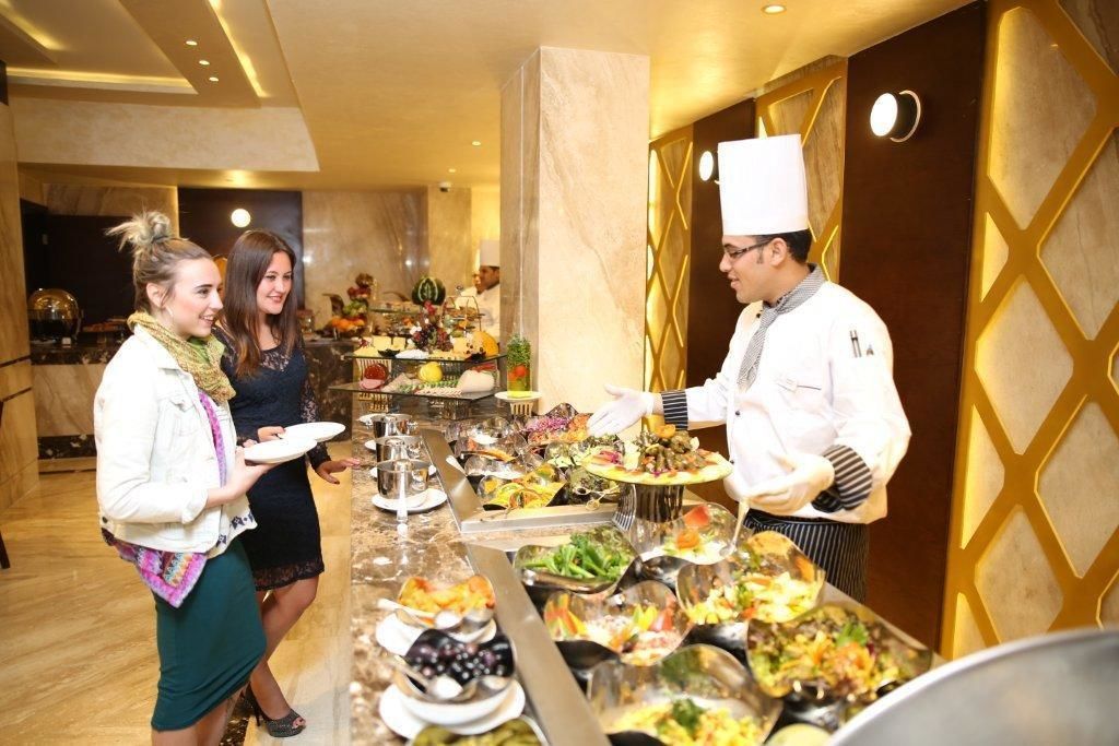 A buffet setup with various dishes and a waiter serving food.