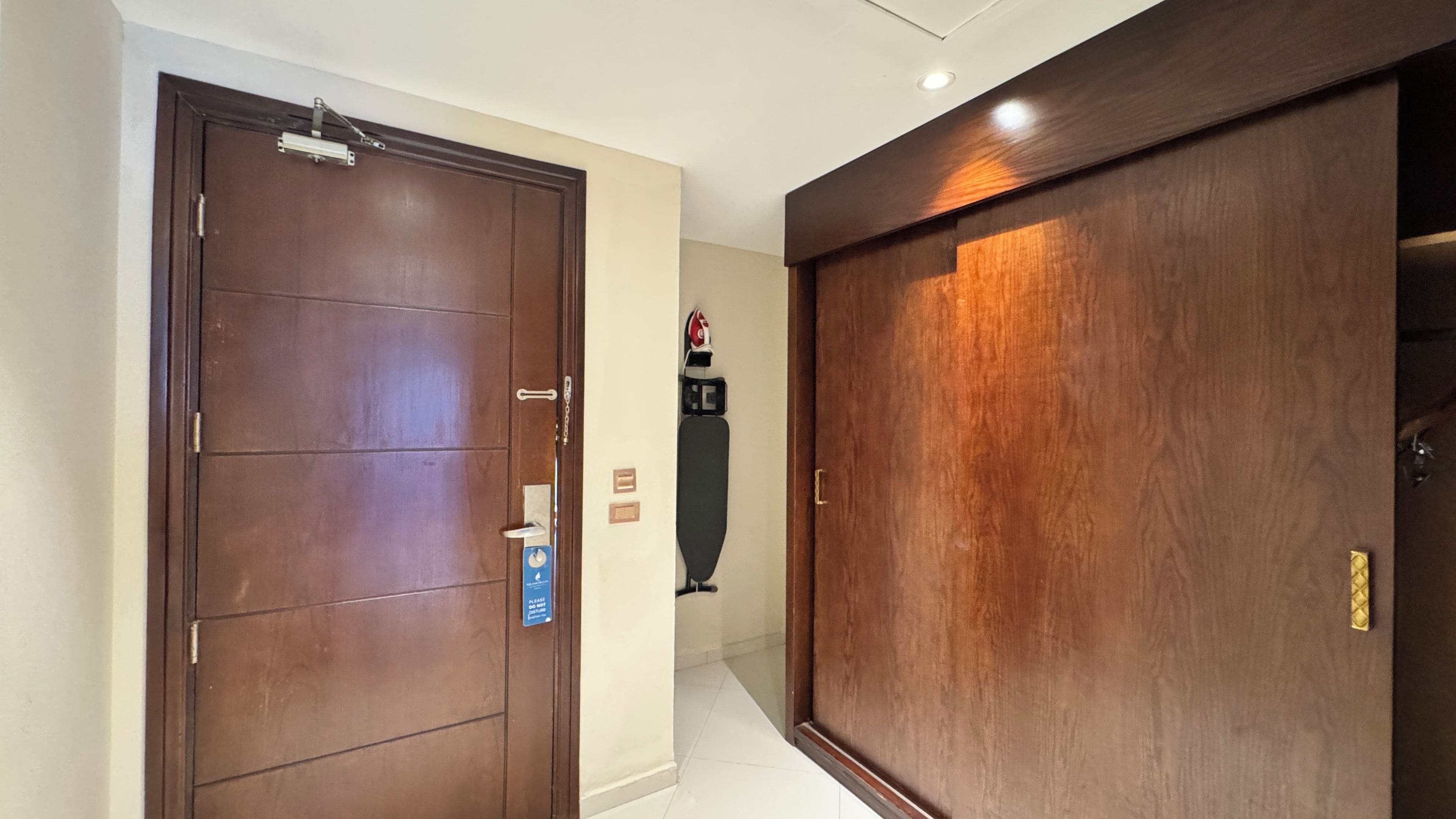 A hallway with two wooden doors, one of which has a security device attached.