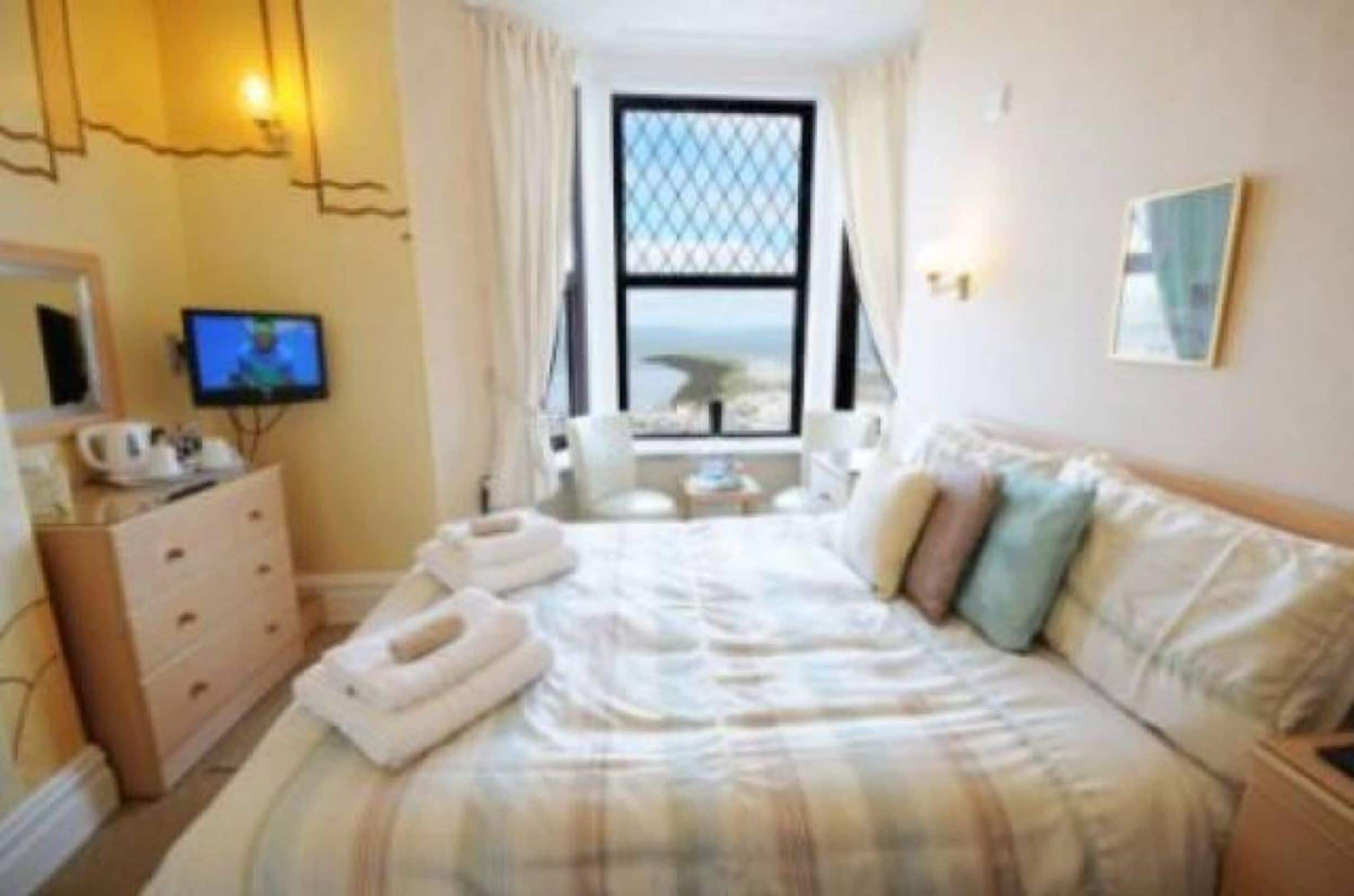 Ein Hotelzimmer mit Bett, Schminktisch, Fernseher und Fenster mit Blick.