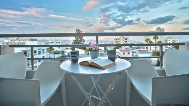 A balcony with a table, two chairs, a book, and two mugs.