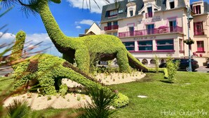 A dinosaur-shaped topiary in a garden with a hotel in the background. - Hôtel Outre-Mer (Villers-sur-Mer)