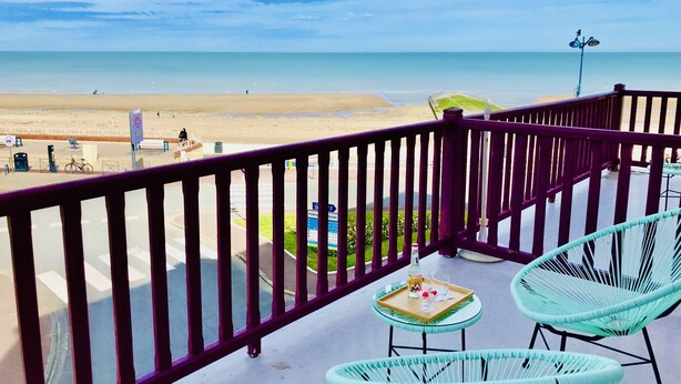 A balcony with a view of the beach, featuring wicker chairs and a small table with a tray. - Hôtel Outre-Mer (Villers-sur-Mer)
