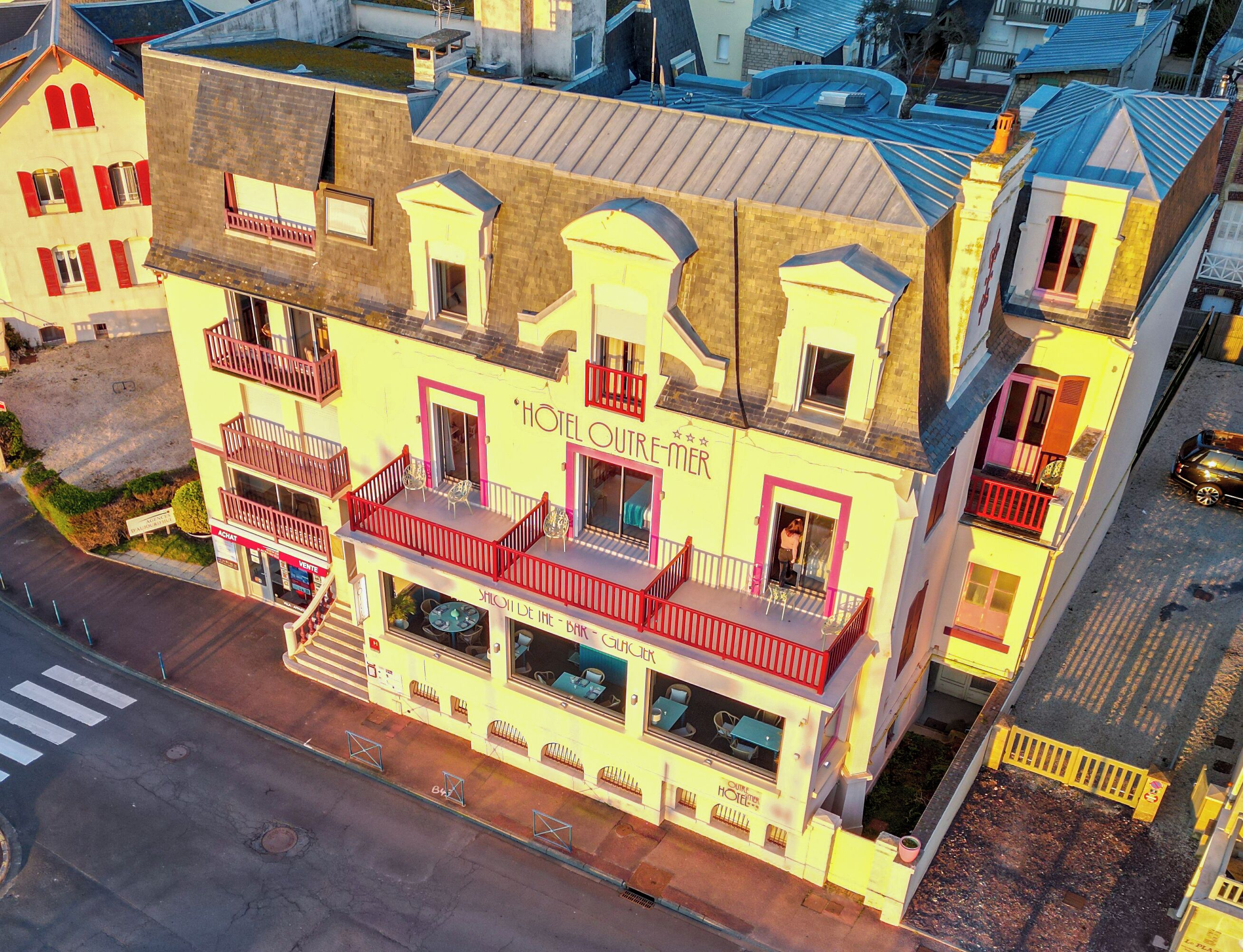 A multi-story hotel with balconies, a ground floor bar, and a visible staircase.