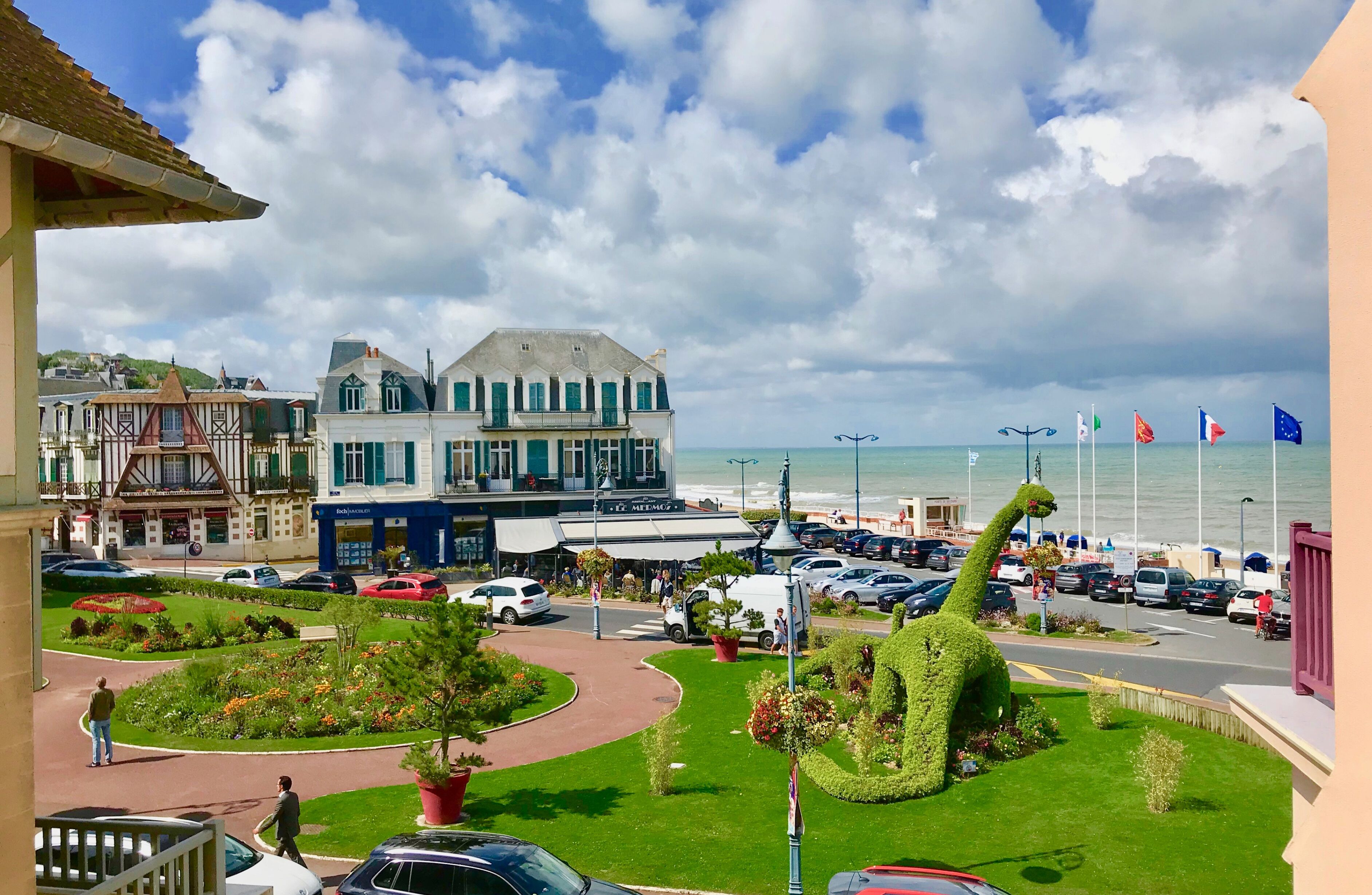 A coastal town with a prominent building, a well-maintained garden, and a sea view.