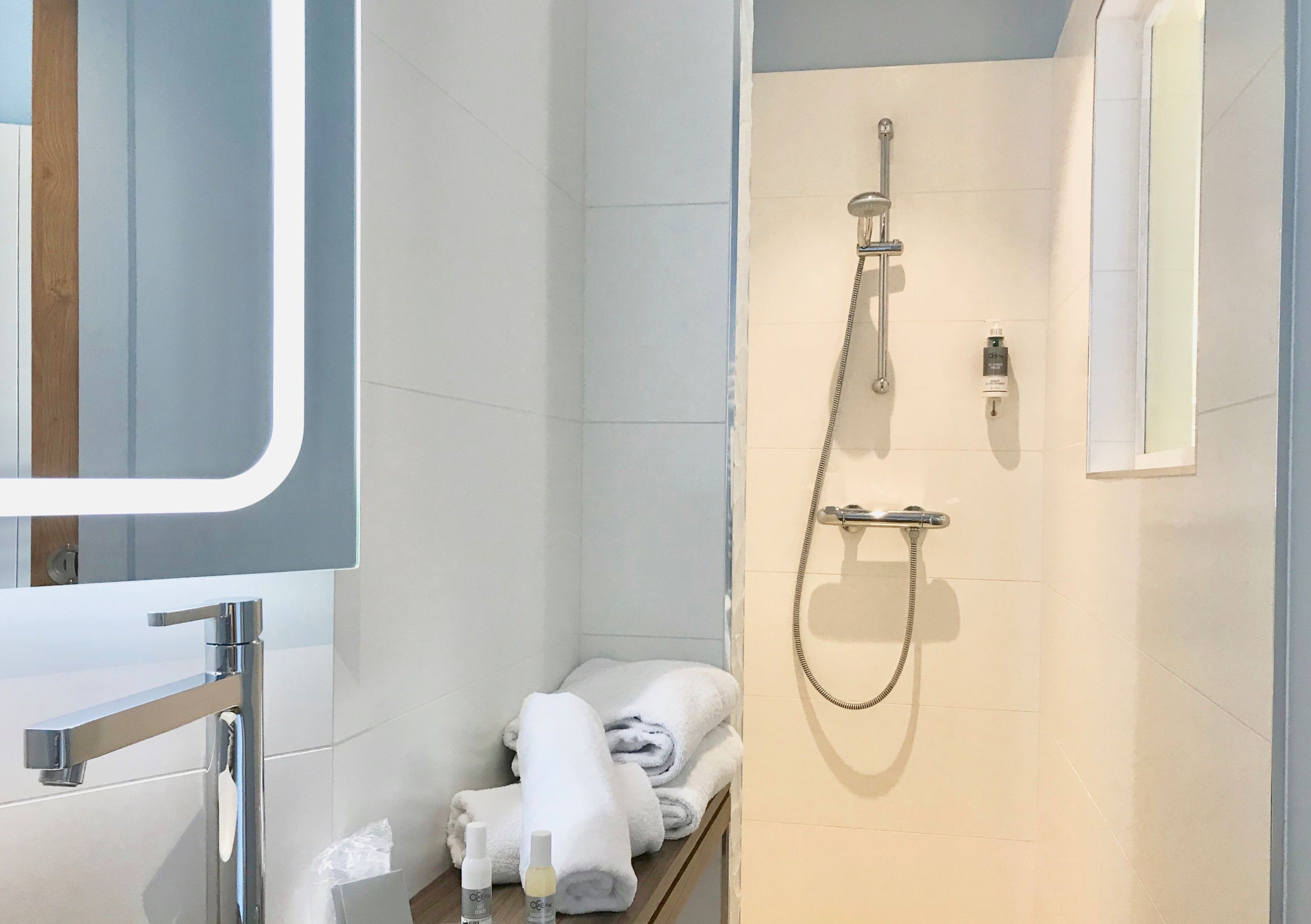 A modern bathroom with a shower, a mirror, and a towel rack.