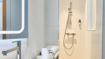 A modern bathroom with a shower, a mirror, and a towel rack.