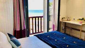 Een slaapkamer met een bed, een bureau en uitzicht op het strand.