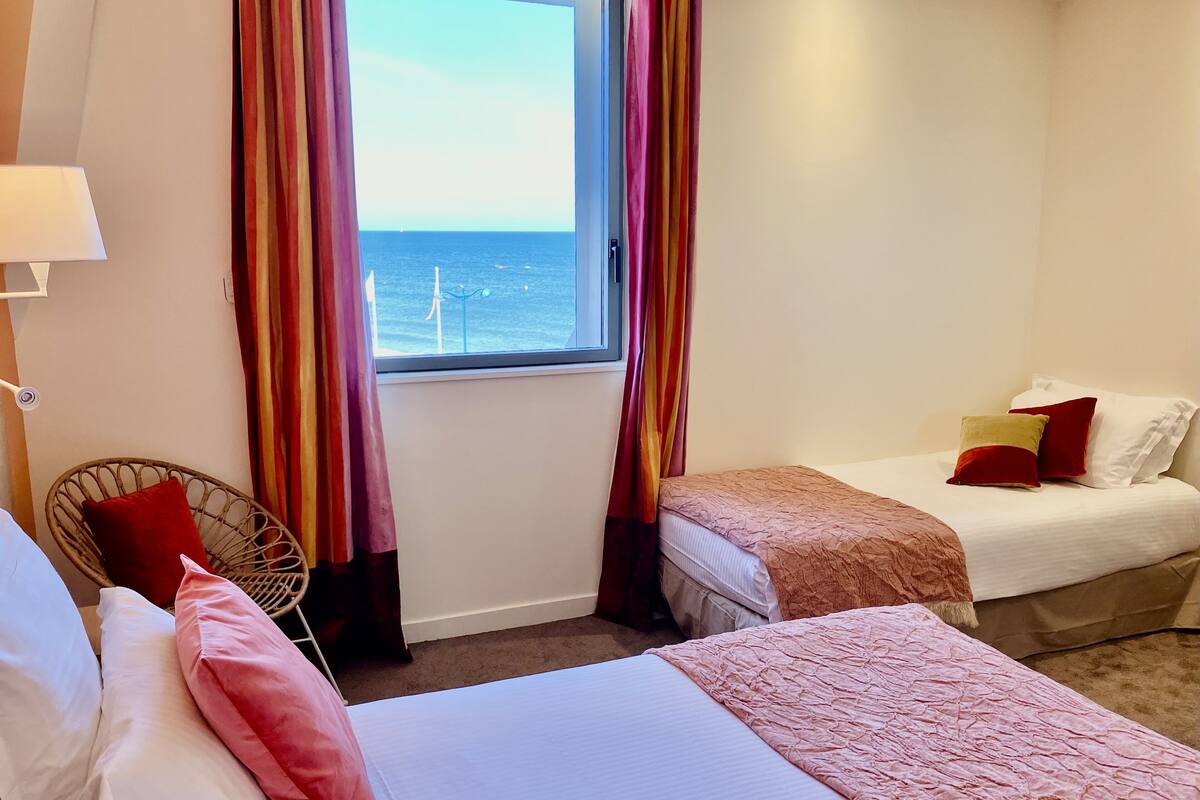 A hotel room with a bed, a chair, and a window with curtains.