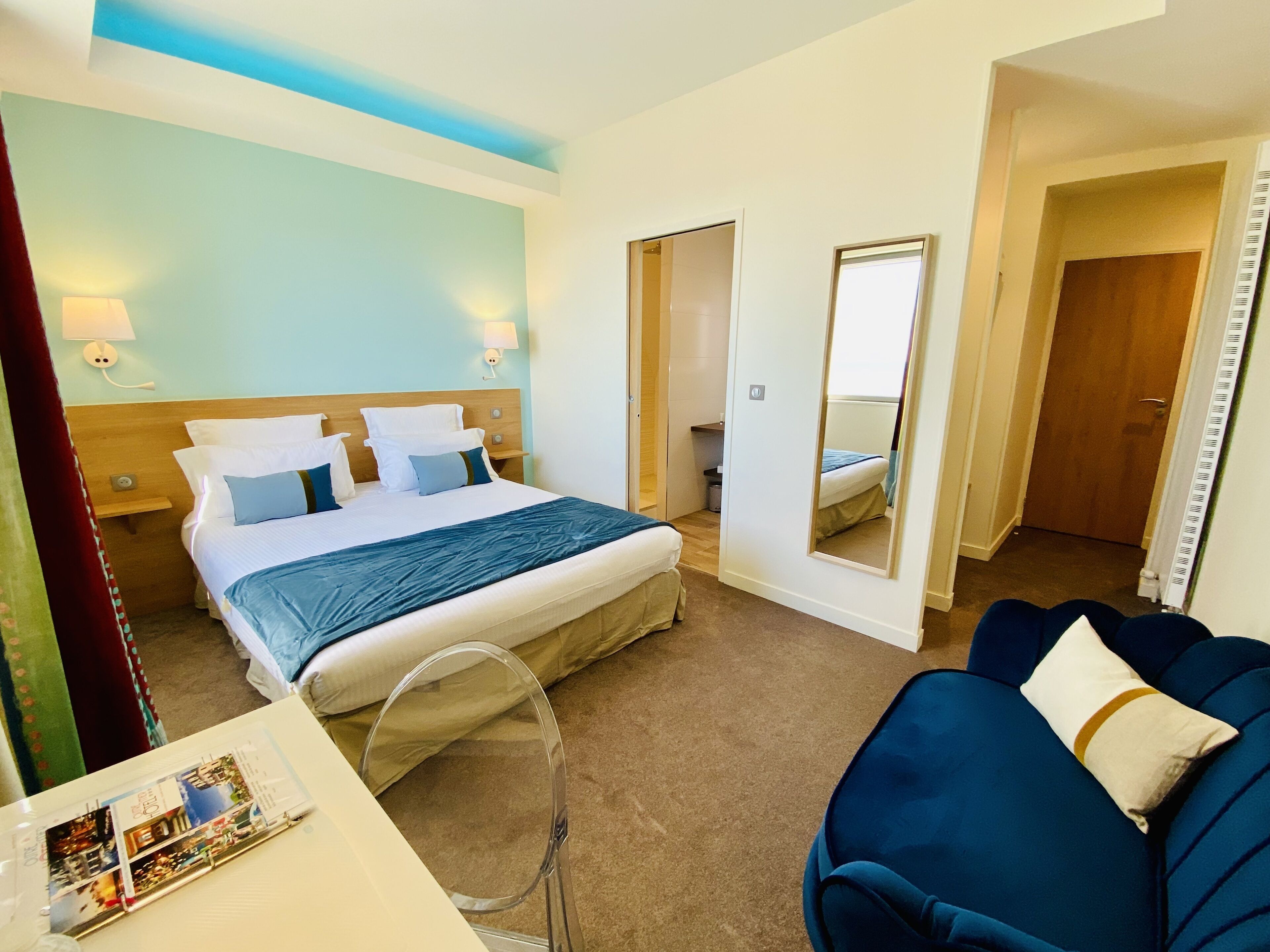 A hotel room with a bed, bedside tables, a mirror, a desk, and a chair.